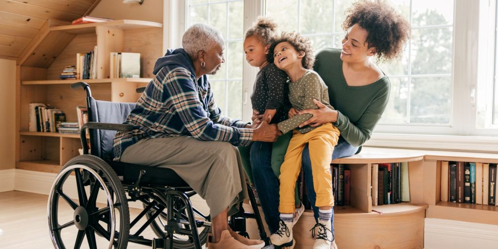 Multiple-Sklerose-Patientin im Rollstuhl mit Tochter und Enkelkindern
